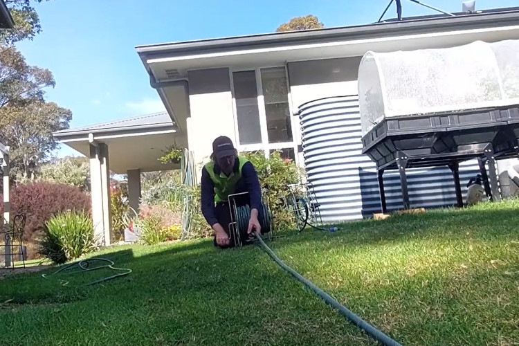 With the workday done, the ulladulla downpipe cleaner is rolling up his hose.